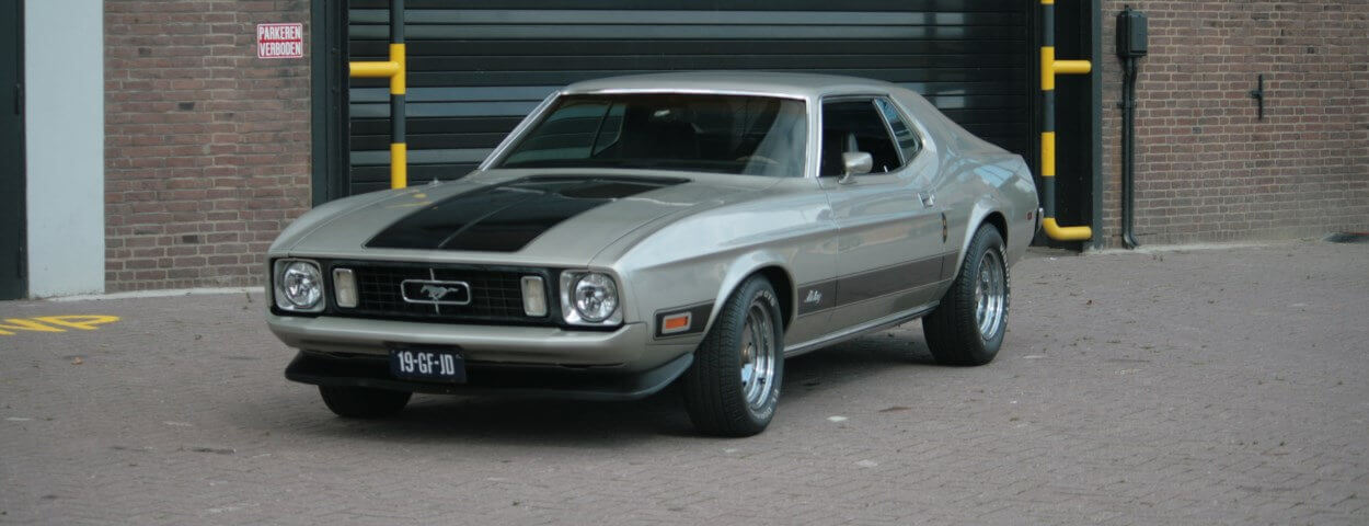 Ford mustang te huur als trouwauto welke voor een oud gebouw staat